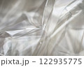 Crumpled clear plastic background, abstract glossy broken surface texture with creases 122935775