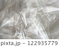 Crumpled clear plastic background, abstract glossy broken surface texture with creases 122935779