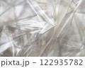 Crumpled clear plastic background, abstract glossy broken surface texture with creases 122935782
