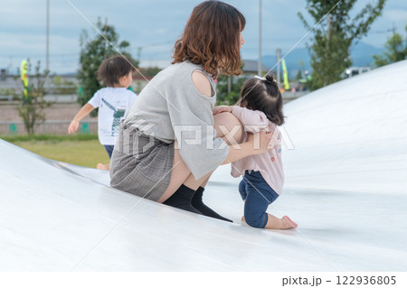 【巨大な遊具で、つかまり立ちする乳幼児とママ】 122936805