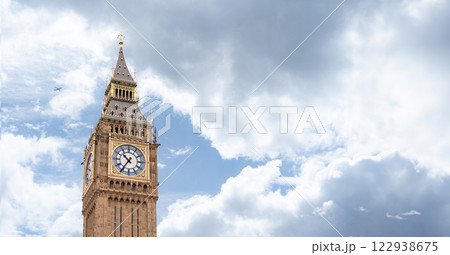 Big Ben iconic clock tower bathed in daylight, emphasizing the golden accents and intricate design against the backdrop of a cloudy sky, for promoting London historic landmarks. 122938675