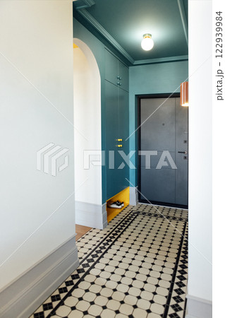 The front door and the hallway. Stylish and elegant interior of the room. Bright yellow accents on the blue built-in wardrobe. The front door and the hallway. Stylish and elegant interior of the room. Bright yellow accents on the blue built-in wardrobe. 122939984