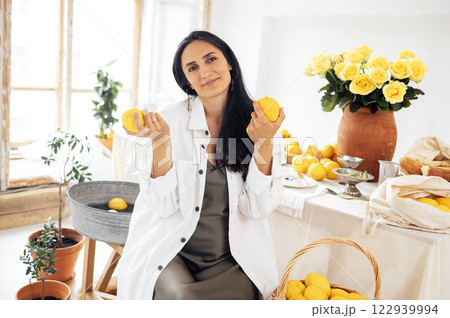 A charming girl is sitting at a table and holding lemons. A young pregnant woman in a green satin dress and shirt is dining in a rustic vintage interior. A charming girl is sitting at a table and holding lemons. A young pregnant woman in a green satin dress and shirt is dining in a rustic vintage interior. 122939994