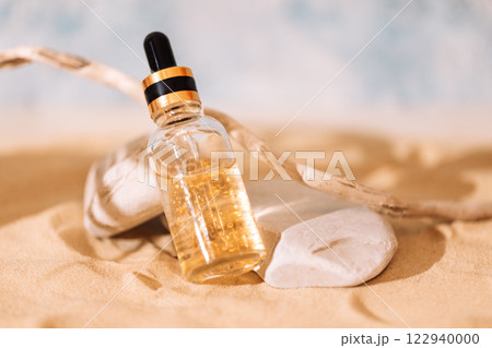 Mockup of bottle of cosmetics with pipette and transparent liquid with gold particles on sand. Sunscreen essence in glass tube on beach. Mockup of bottle of cosmetics with pipette and transparent liquid with gold particles on sand. Sunscreen essence in glass tube on beach. 122940000