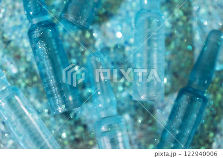 Close-up of blue ampoules with intense moisturizing concentrate with hyaluronic acid and vitamins on shiny sparkling background. Close-up of blue ampoules with intense moisturizing concentrate with hyaluronic acid and vitamins on shiny sparkling background. 122940006