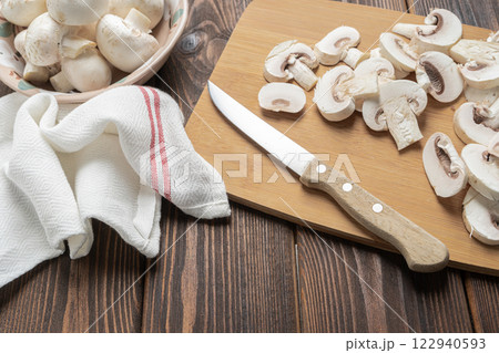 Fresh champignon mushrooms. Cutting champignon on cutting board. 122940593