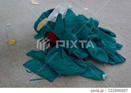 Discarded green medical scrubs and gloves on operating room floor 122940807