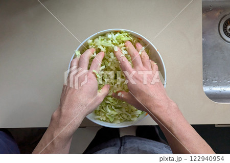 Hands vigorously tossing shredded cabbage in large bowl, salad becoming bright symbol of fresh nutrition, salad capturing crisp texture, salad perfect for quick healthy lunches 122940954