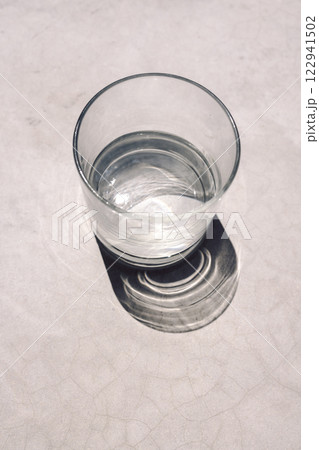Close-up of a glass of clean water on a concrete table. Healthy mineral water and bright sunlight Close-up of a glass of clean water on a concrete table. Healthy mineral water and bright sunlight 122941502
