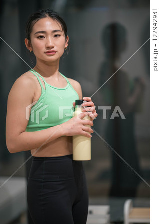 室内のジムでトレーニングの合間に水分補給をする若い女性 122942931