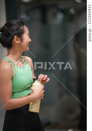 室内のジムでトレーニングの合間に水分補給をする若い女性 122942932