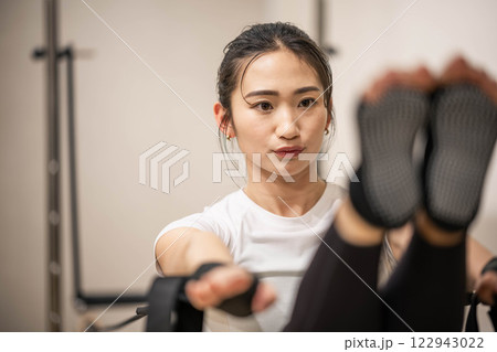 室内のジムでマシンピラティスをする若い女性 室内のジムでマシンピラティスをする若い女性 122943022