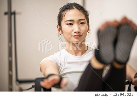 室内のジムでマシンピラティスをする若い女性 122943023