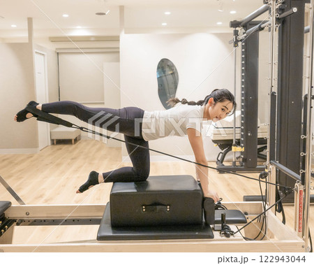 室内のジムでマシンピラティスをする若い女性 室内のジムでマシンピラティスをする若い女性 122943044