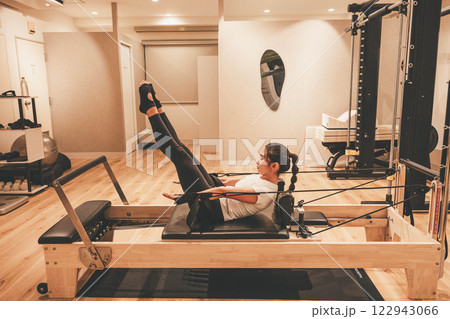 室内のジムでマシンピラティスをする若い女性 122943066