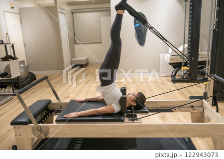 室内のジムでマシンピラティスをする若い女性 122943073