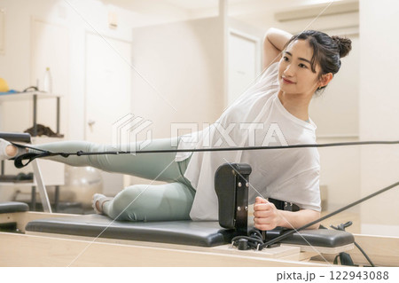 室内のジムでマシンピラティスをする若い女性 122943088