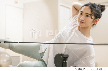 室内のジムでマシンピラティスをする若い女性 室内のジムでマシンピラティスをする若い女性 122943089