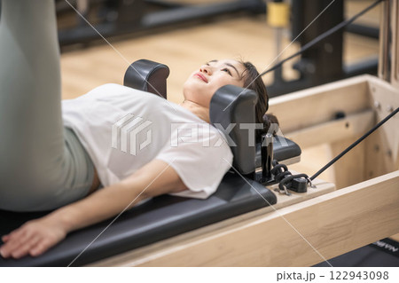 室内のジムでマシンピラティスをする若い女性 122943098