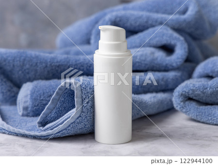 White blank one pump bottle near blue bath towel closeup, mockup. Natural handmade cosmetic White blank one pump bottle near blue bath towel closeup, mockup. Natural handmade cosmetic 122944100