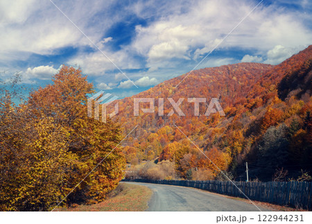 Driving a car along a mountain winding road. Empty road. View from a car to the autumn mountain landscape Driving a car along a mountain winding road. Empty road. View from a car to the autumn mountain landscape 122944231