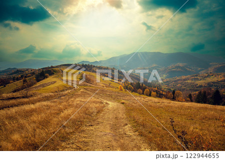 Mountain landscape on a sunny autumn day. View of the mountain slopes and dirt road. Beautiful nature landscape. Carpathian mountains. Ukraine Mountain landscape on a sunny autumn day. View of the mountain slopes and dirt road. Beautiful nature landscape. Carpathian mountains. Ukraine 122944655
