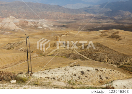 Vast desert landscape in Iran showcasing rolling hills and power lines 122946868