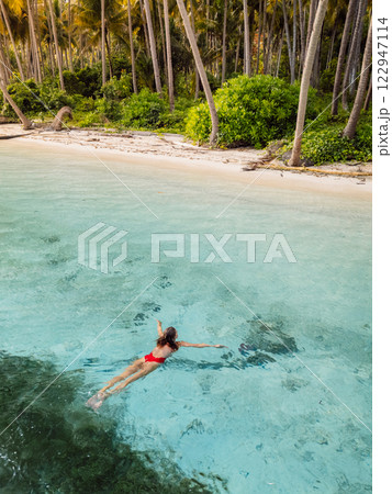Woman swims in tropical ocean near beach on her vacations. Aerial view Woman swims in tropical ocean near beach on her vacations. Aerial view 122947114