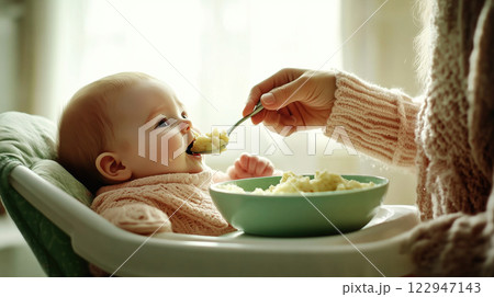 Mother feeding her baby solid food with a spoon 122947143