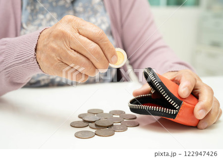 Asian senior or elderly old lady woman holding counting coin money in bag. Poverty, saving problem in retirement. 122947426