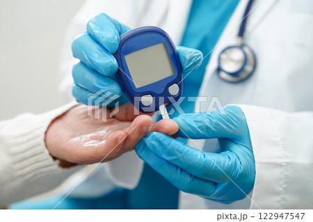 Asian doctor using digital glucose meter for check sample blood sugar level to treatment diabetes. 122947547