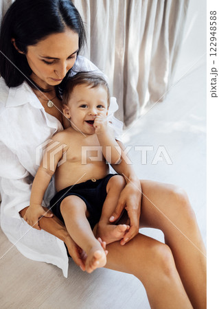A young attractive woman holds her smiling son in her arms. A funny boy is playing with his mom. A young attractive woman holds her smiling son in her arms. A funny boy is playing with his mom. 122948588