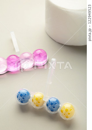 Toilet balls and toilet paper on grey background. Clean the toilet bowl with cleaning and refreshing balls. Vertical photo Toilet balls and toilet paper on grey background. Clean the toilet bowl with cleaning and refreshing balls. Vertical photo 122949523