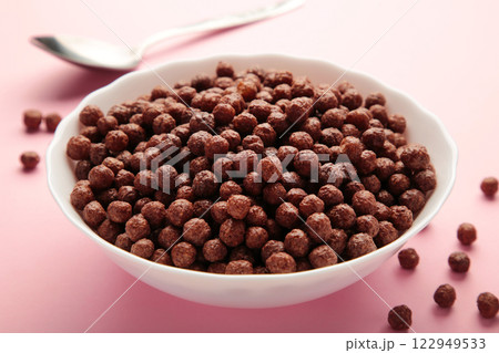 Chocolate cereal corn balls in a white bowl on a pink background. Chocolate cereal corn balls in a white bowl on a pink background. 122949533