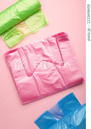 A lot of colored plastic bags rolls on a pink background. Vertical photo. A lot of colored plastic bags rolls on a pink background. Vertical photo. 122949609