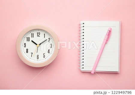 Empty white notebook top view with pink alarm clock on pink background 122949796