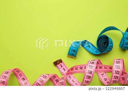 Blue and pink plastic measure tape with metric scale over on green background. 122949807