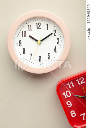 Pink and red wall clock on grey background. Vertical photo Pink and red wall clock on grey background. Vertical photo 122949849