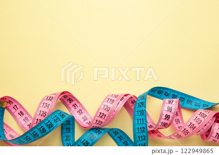 Blue and pink plastic measure tape with metric scale over on color beige background. 122949865
