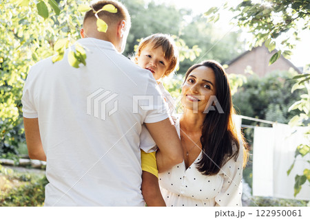 Cute family in light casual clothes in garden on terrace of their house. Cute family in light casual clothes in garden on terrace of their house. 122950061