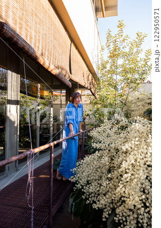 Woman Admiring Blooming Flowers on Balcony 122950571