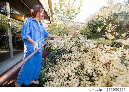 Woman Admiring Blooming Flowers on Balcony 122950585