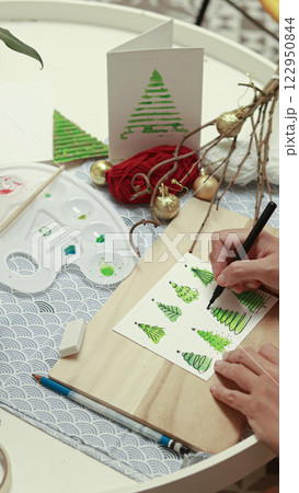 Drawing and adding details to a watercolor Christmas tree illustration that shows steps of designing a handmade greeting card for the holiday season Drawing and adding details to a watercolor Christmas tree illustration that shows steps of designing a handmade greeting card for the holiday season 122950844