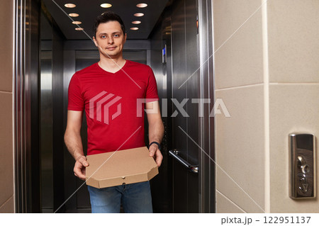 Deliveryman holding pizza box in elevator, food delivery to your home. 122951137