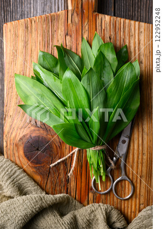 Bunch of vibrant green bear's garlic on a wooden cutting board Bunch of vibrant green bear's garlic on a wooden cutting board 122952248