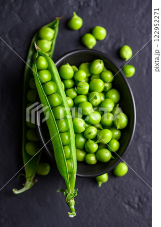 Green sugar snap peas in a simple bowl on a dark backdrop 122952271