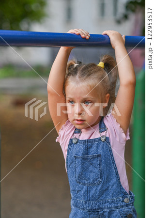 a girl is playing on a crossbar. vertical a girl is playing on a crossbar. vertical 122953517
