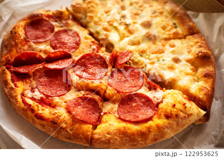 A freshly baked half-and-half pizza with crispy pepperoni and a cheesy white sauce topping, served hot and ready to enjoy A freshly baked half-and-half pizza with crispy pepperoni and a cheesy white sauce topping, served hot and ready to enjoy 122953625