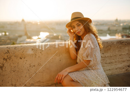 Portrait of happy tourist in hat at dawn enjoys cityscape. Traveling in Europe. Concept tourism. 122954677