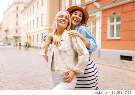 Happy women walk along city streets on sunny day. Young girlfriends having fun outdoors. Lifestyle. Happy women walk along city streets on sunny day. Young girlfriends having fun outdoors. Lifestyle. 122954712